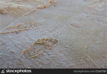 Footprints on sand with textured background.
