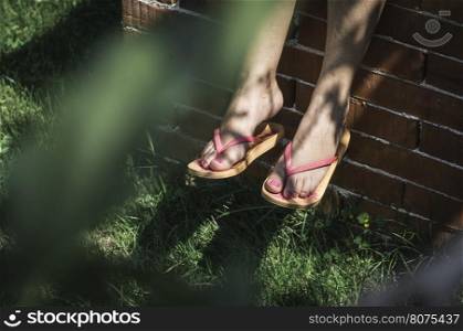 Foots on green grass. Pink thongs