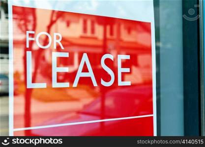 For Lease sign on red in window reflecting street scene