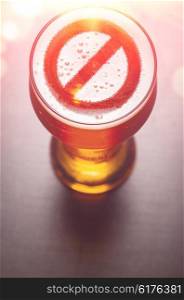 forbidden symbol on foam in beer glass on black table, view from above