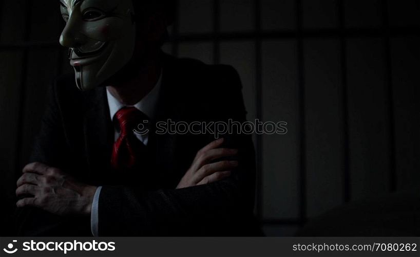 Foreboding shot of Anonymous hacker man in prison