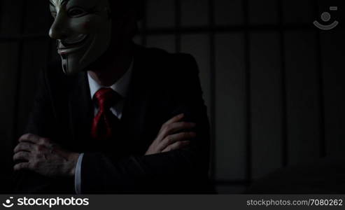 Foreboding shot of Anonymous hacker man in prison