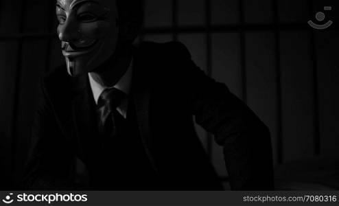 Foreboding shot of Anonymous hacker man in prison (B/W Version)