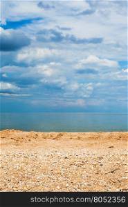 Foreground focus - sand and shelly beach and dark blue clouds over sea. Coastline of Sea of Azov, Temryuk bay, Golubitskaya resort, Taman peninsula, Kuban, Russia