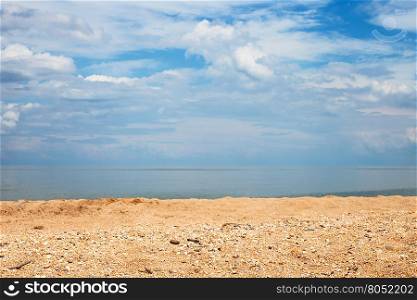 Foreground focus - sand and shelly beach and white clouds over sea. Coastline of Sea of Azov, Temryuk bay, Golubitskaya resort, Taman peninsula, Kuban, Russia