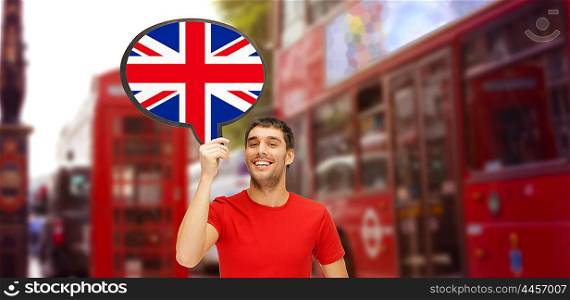 foreign language, english, travel, people and communication concept - smiling young man holding text bubble of british flag over london city street background