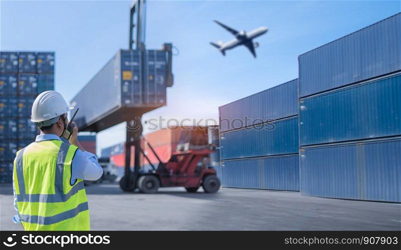 Foreman control loading Containers box from Cargo freight ship for import export.Thailand construction worker or supervisor or architect with clipboard on a building site in Asia