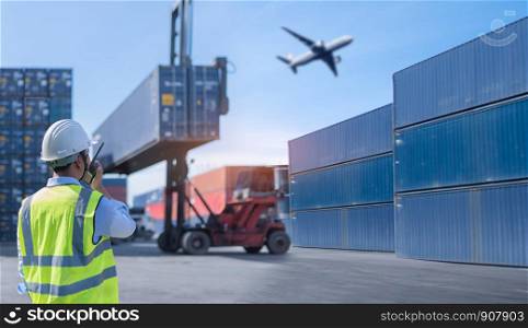 Foreman control loading Containers box from Cargo freight ship for import export.Thailand construction worker or supervisor or architect with clipboard on a building site in Asia
