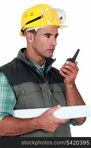 foreman with blueprints holding talkie walkie