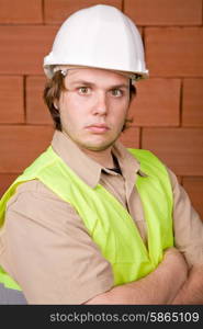foreman with white hat with a brick wall as background