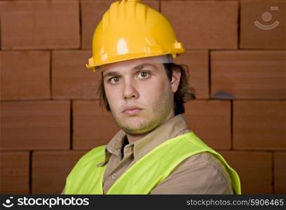 foreman with yellow hat with a brick wall as background