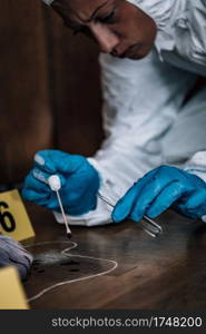 Forensic Investigator collecting blood evidence from a crime scene