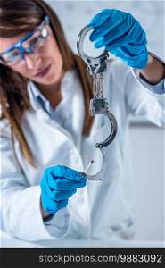 Forensic science expert examining handcuffs, collecting blood