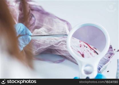 Forensic science expert examining traces of blood on a piece of cloth collected at a crime scene