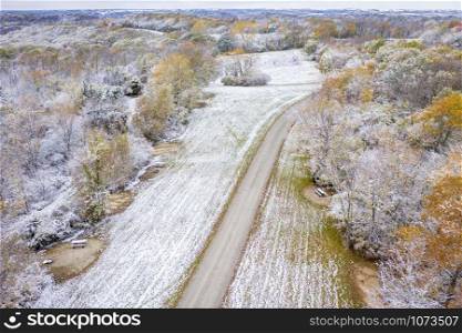 Forest and harvested corn field dusted by early snow, aerial view of Honey Creek Conservation Area in western Missouri