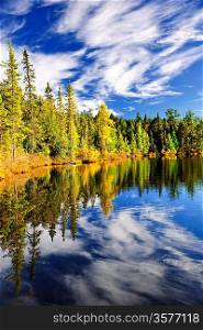 Forest and sky reflecting in lake