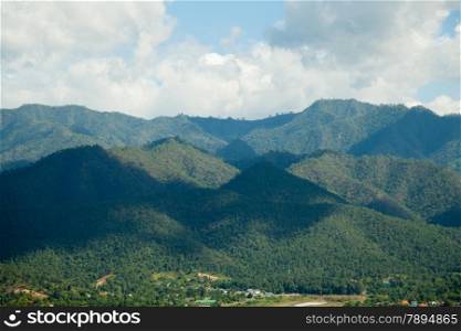 forest-covered mountains. Tree-covered mountains throughout the The shadow of a cloud-covered sky covered mountain peaks.