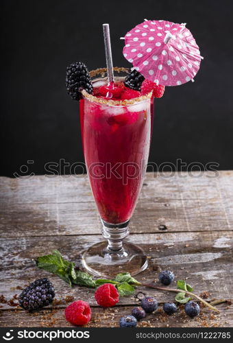 forest fruit cocktail in a glass on a wooden base decorated with blackberries