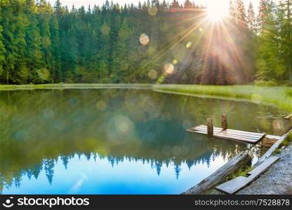 Forest lake in the mountains with blue water, morning light and shining sun