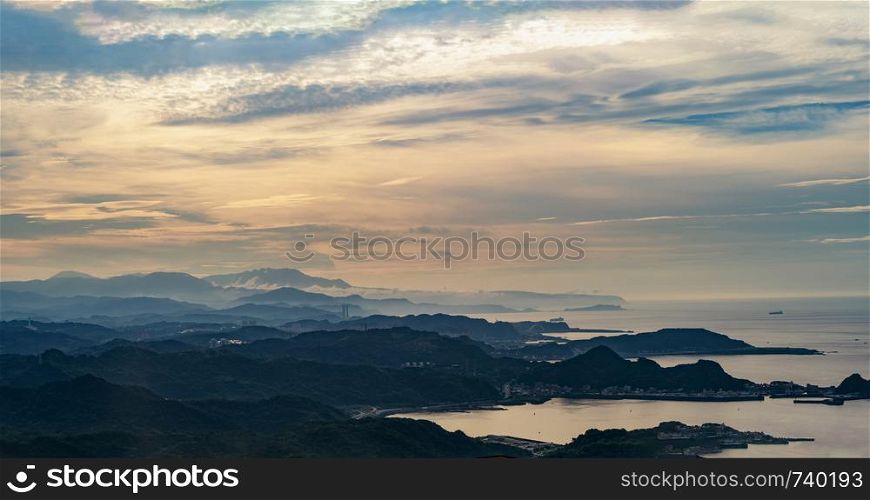 Forest trees and mountains range with visible silhouettes with fog and cloud sky at sunset in New Taipei City, Taiwan. Natural landscape