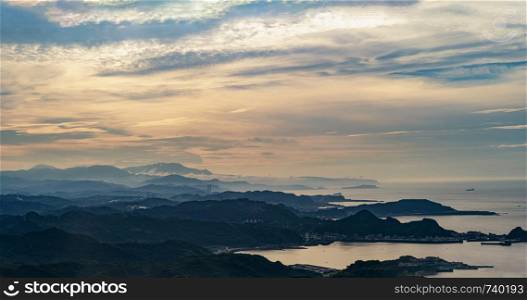 Forest trees and mountains range with visible silhouettes with fog and cloud sky at sunset in New Taipei City, Taiwan. Natural landscape