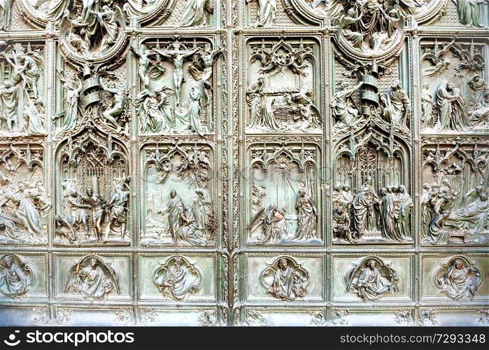 Forged doors with bronze bas reliefs at facade of cathedral Duomo di Milano. Italy