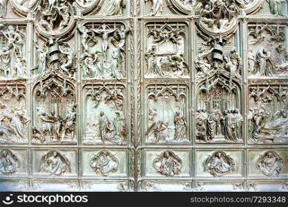 Forged doors with bronze bas reliefs at facade of cathedral Duomo di Milano. Italy