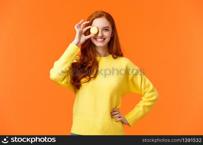 Forget about diet, lets enjoy. Cheerful and happy, smiling redhead woman holding small tasty macaron over eye and grinning, baking own desserts, promote awesome cafe with delicious food.. Forget about diet, lets enjoy. Cheerful and happy, smiling redhead woman holding small tasty macaron over eye and grinning, baking own desserts, promote awesome cafe with delicious food