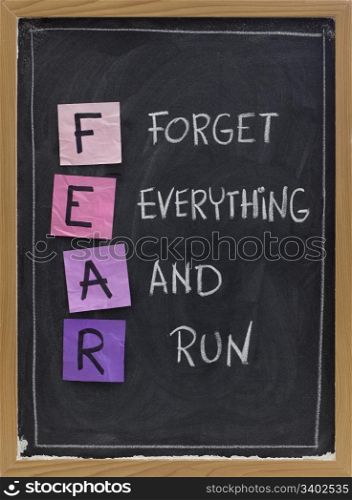forget everything and run - FEAR acronym, shutting down or panic response concept, white chalk handwriting and sticky notes on blackboard