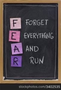forget everything and run - FEAR acronym, shutting down or panic response concept, white chalk handwriting and sticky notes on blackboard