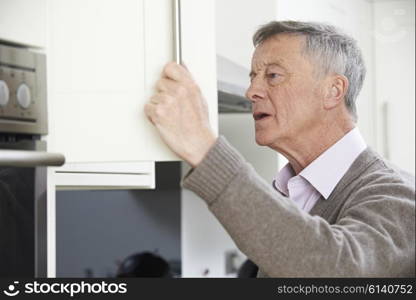 Forgetful Senior Man Looking In Cupboard