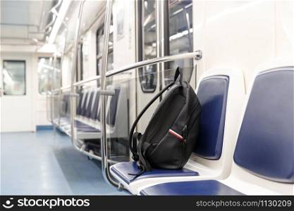 Forgotten leather black backpack/bag or bomb to commit a terrorist attack lies on a seat in subway train, public transport. Threat of terrorism.