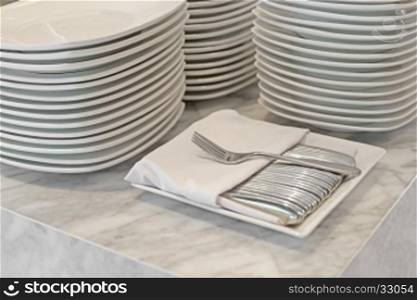 fork and empty white plate on buffet line