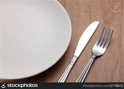 Fork and knife with empty plate on wooden table