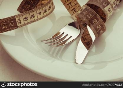 Fork and knife with meter on the empty white plate, diet concept