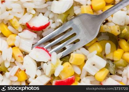 Fork in a salad with fresh vegetables and crab sticks
