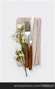 Fork, knife and flowers on white background, flat lay