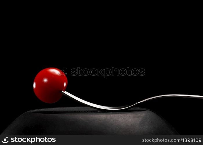Fork with cherry tomato close-up. Isolated image on a black background. Macro photo. cooking concept.. Fork with cherry tomato close-up. Isolated image on a black background. Macro photo. cooking concept