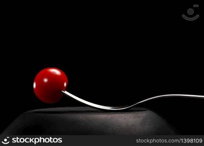 Fork with cherry tomato close-up. Isolated image on a black background. Macro photo. cooking concept.. Fork with cherry tomato close-up. Isolated image on a black background. Macro photo. cooking concept