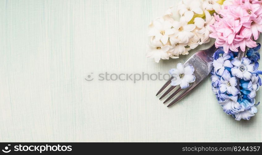 Fork with hyacinths flowers on light green background, top view, banner for website or placard. Place setting concept. Spring or Easter food.