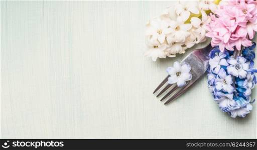 Fork with hyacinths flowers on light green background, top view, banner for website or placard. Place setting concept. Spring or Easter food.