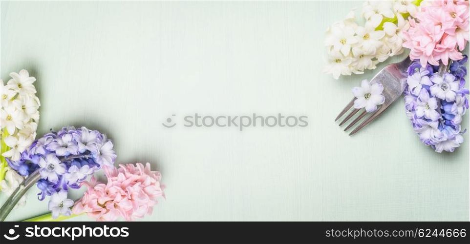Fork with spring hyacinth flowers on light green shabby rustic background, top view, banner. Festive table place setting and cooking.