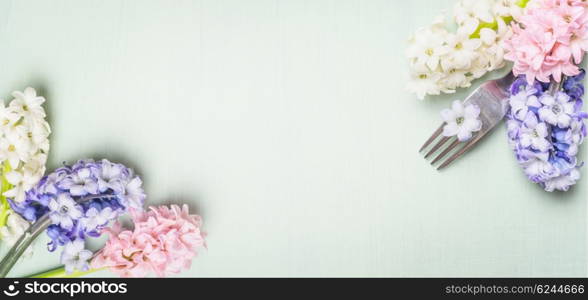 Fork with spring hyacinth flowers on light green shabby rustic background, top view, banner. Festive table place setting and cooking.