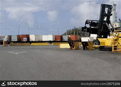 Forklift at a commercial dock with cargo containers in the background