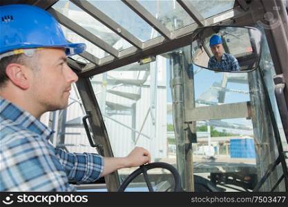 Forklift driver looking in rearview mirror
