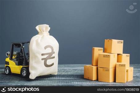Forklift truck carries ukrainian hryvnia money bag near pile of boxes. Profit from trade and exchange of goods. Investments financing in production, taxes, income revenues and costs. Superprofits.