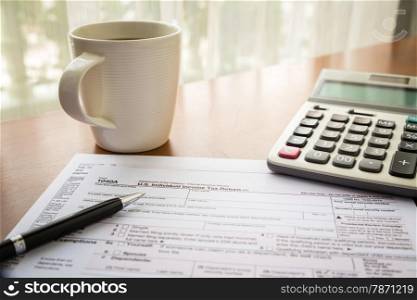 Form 1040A, U.S. Individual income tax return place on table with a cup of coffee, calculator and pen