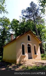 Former chapel restored in the forest with windows and door in arch.
