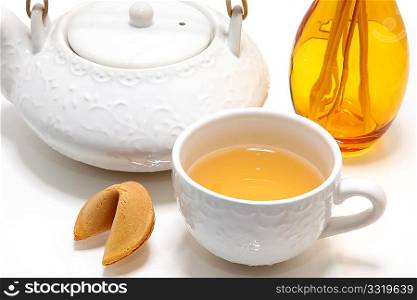 Fortune cookie, chinese green tea with gensing and honey, cup, pot, reed diffuser over white.