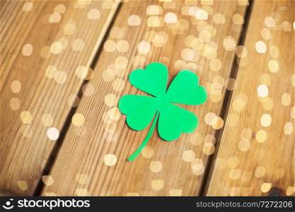 fortune, luck and st patricks day concept - green paper four-leaf clover on wooden background. green paper four-leaf clover on wooden background